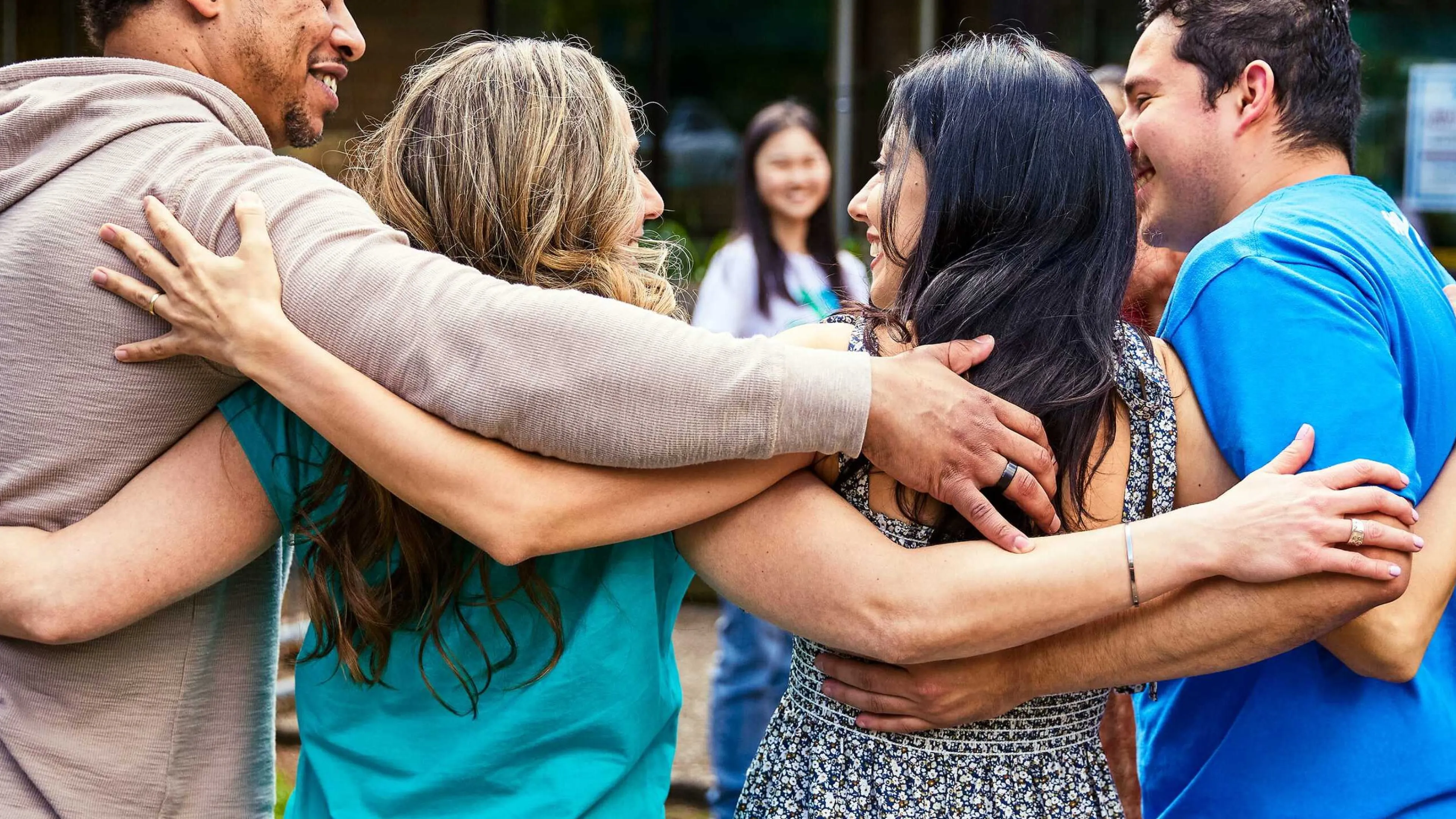 Group of people in a close embrace demonstrating strong community bond during a gathering, possibly supporting the local programs.